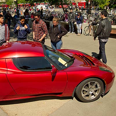 Several men inspecting a Tesla roadster