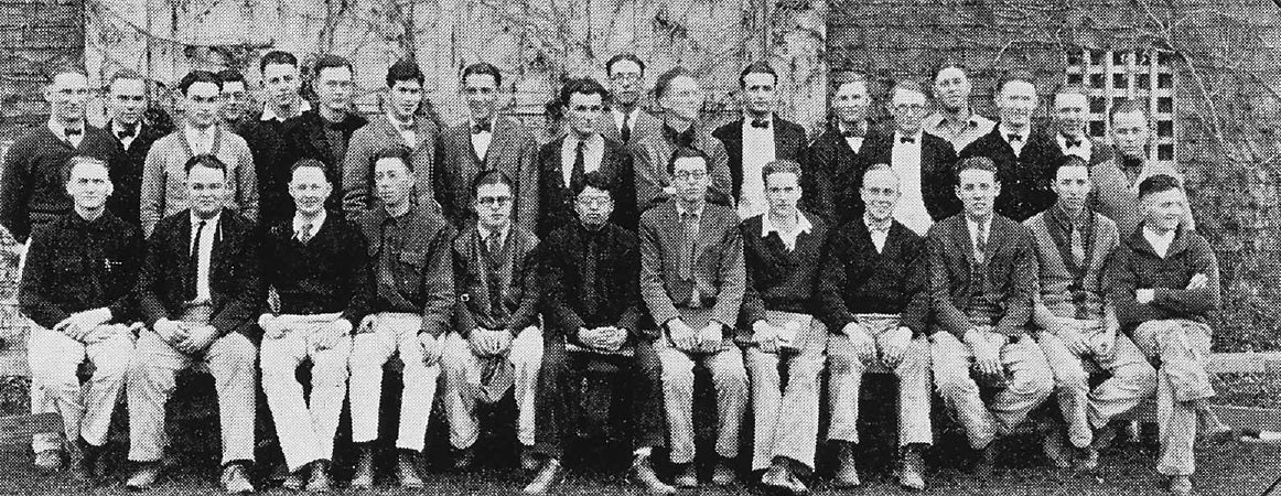 Black-and-white group photograph of about 30 men in blazers and cricket whites outdoors
