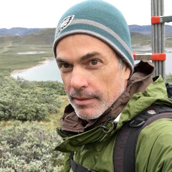 A UC Davis researcher poses for the camera in front of a tundra filled landscape