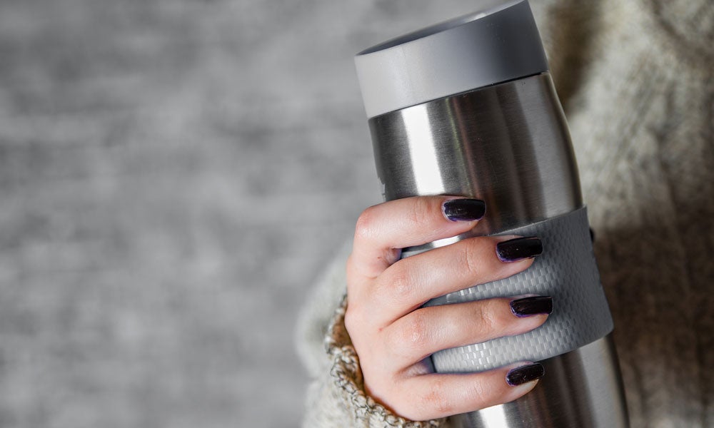 A person holding a travel mug