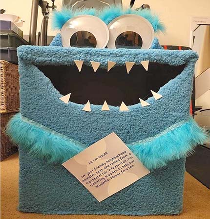 Box decorated to look like happy blue monster with open mouth.