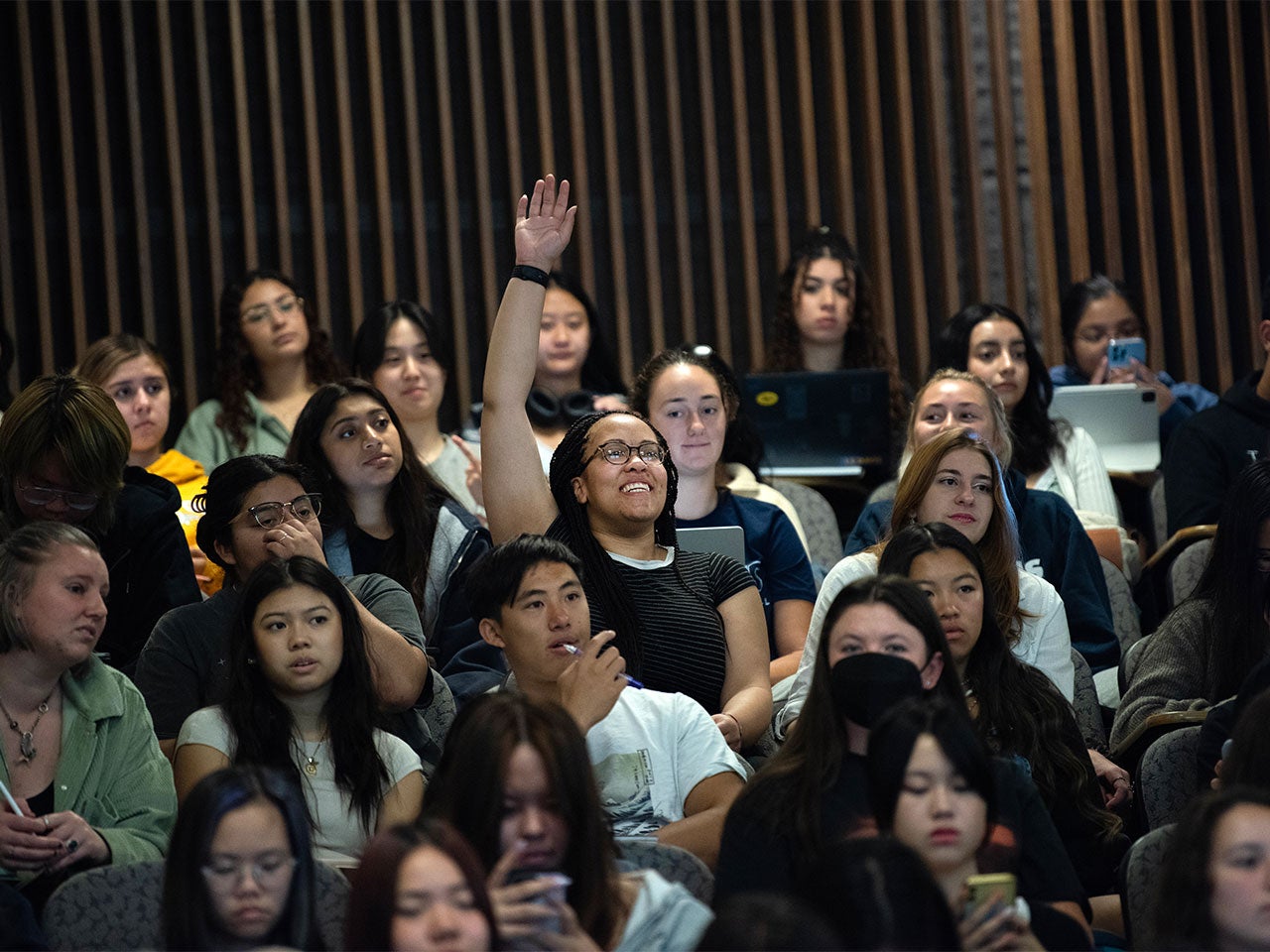 A UC Davis student raises their hand during a class session.
