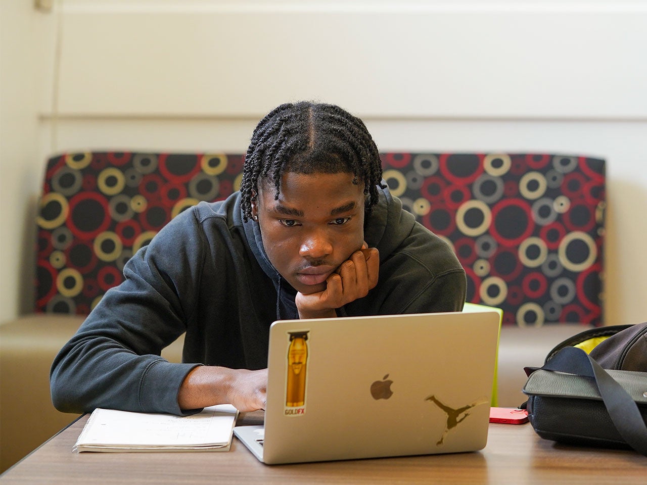 A UC Davis student researches on a silver laptop.