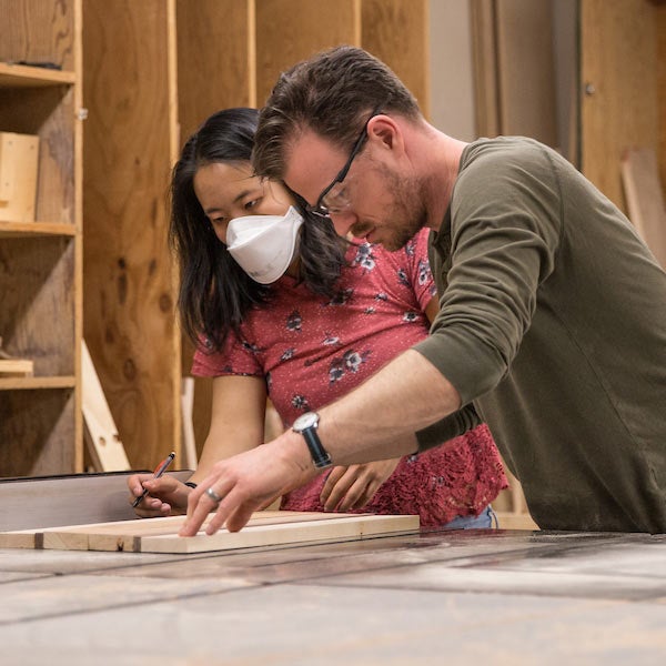 A male and female student cut a piece of wood at the UC Davis craft center