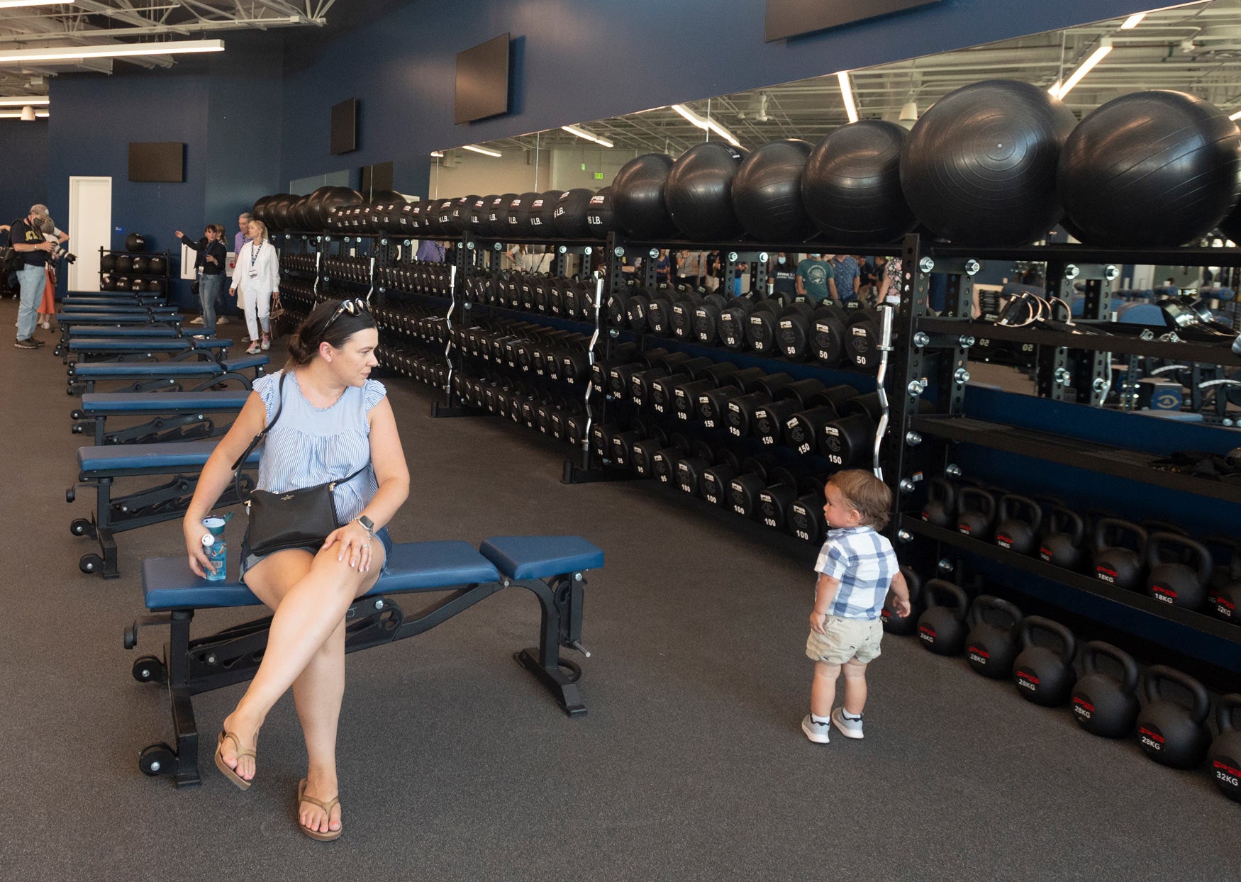 Mother seated with toddler looking at weights, wanting to use them?