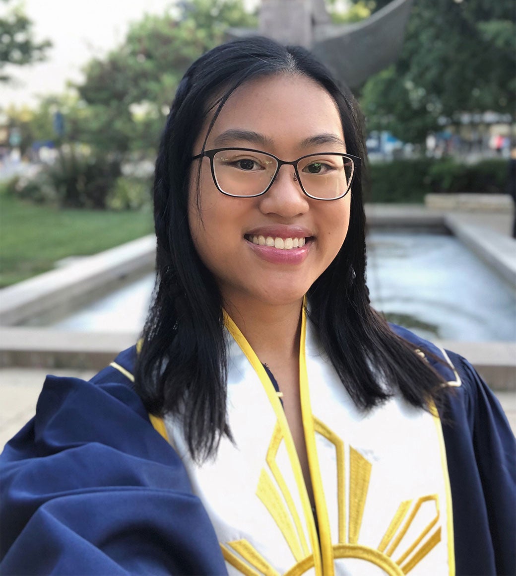 Ellaine Arroyo, smiling and wearing glasses, poses in her graduation gown.