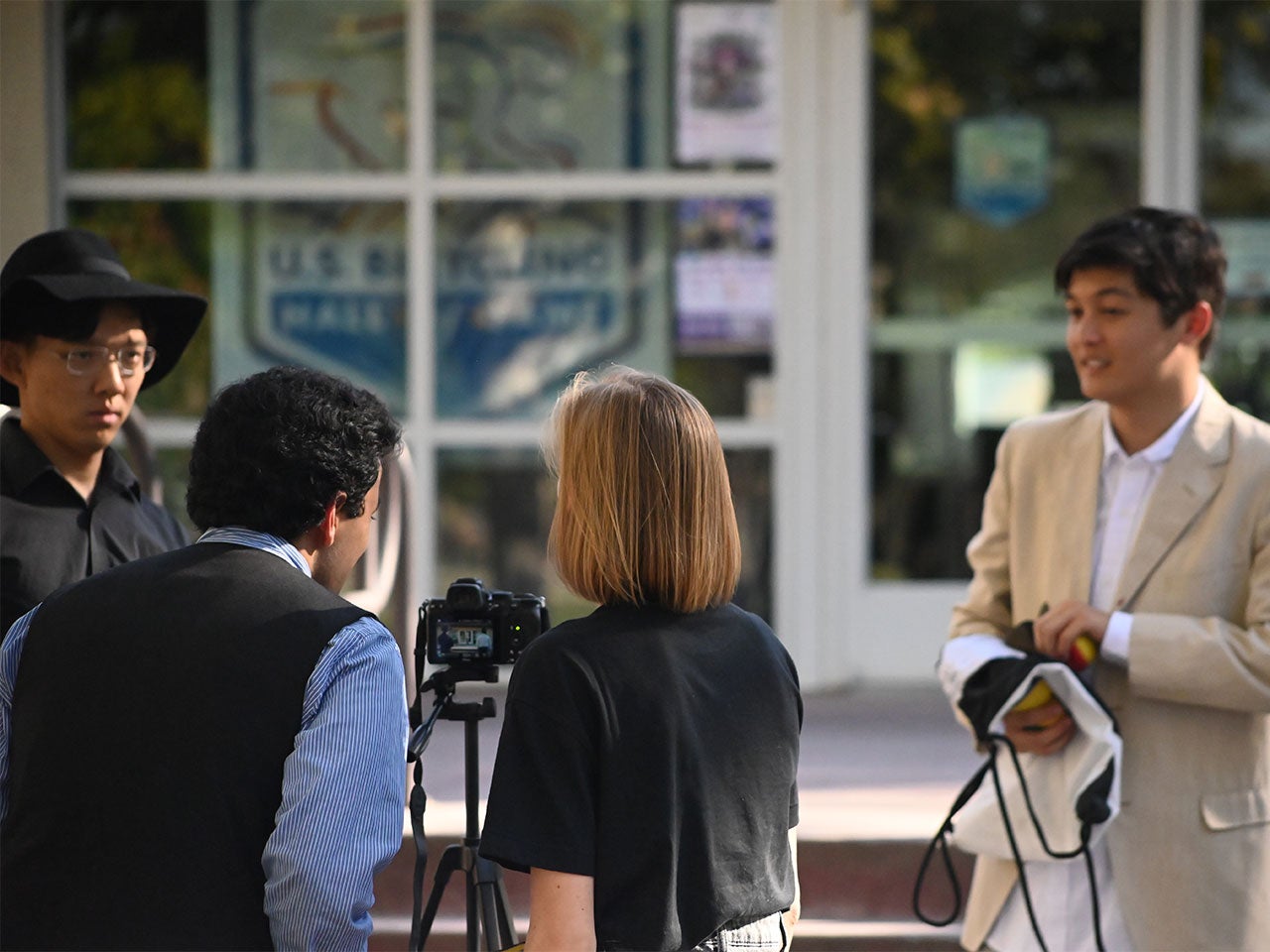 Three UC Davis students review footage while an actor waits for instruction.