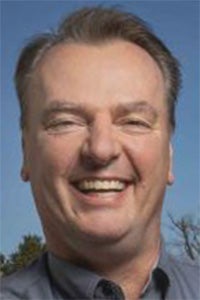 Smiling man headshot photograph against blue sky