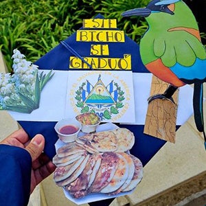 Mortarboard with an El Salvador flag as the bottom layer and images of a parrot, plants, and food with the words "Este Bicho Se Graduo (This Beast Graduated)"