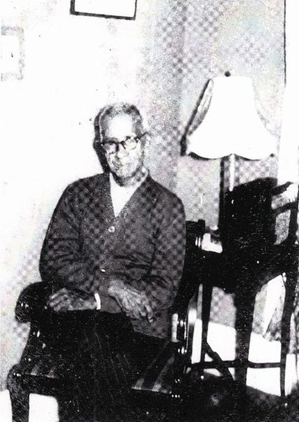 Black and white photo of man sitting in chair.
