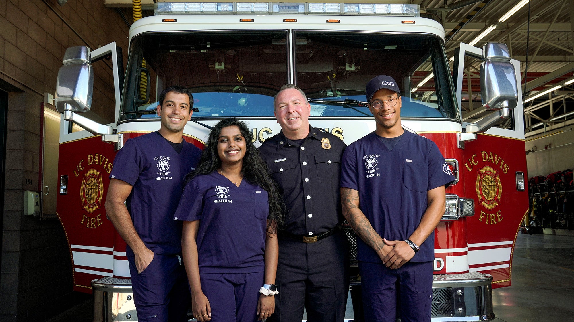 Student EMTs and fire chief pose for photo in front of fire truck.