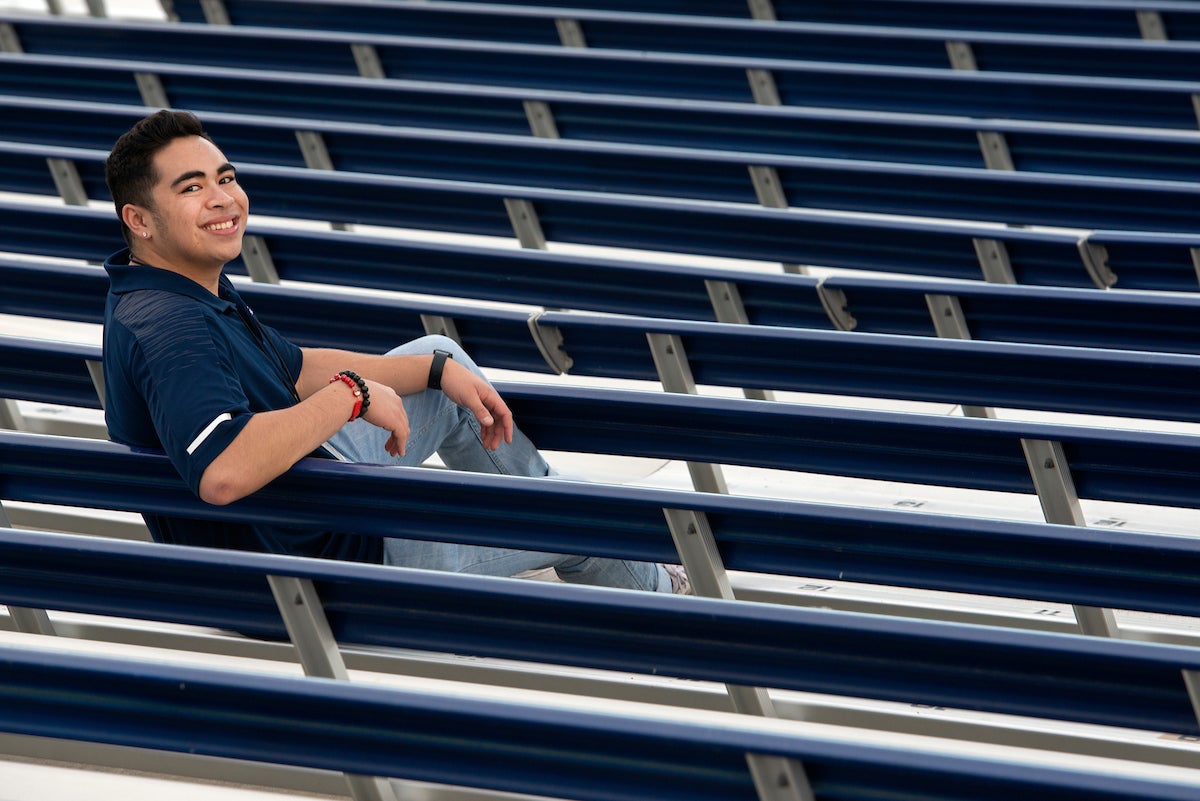 A student sits in stadium stands and looks back over his shoulder at UC Davis.