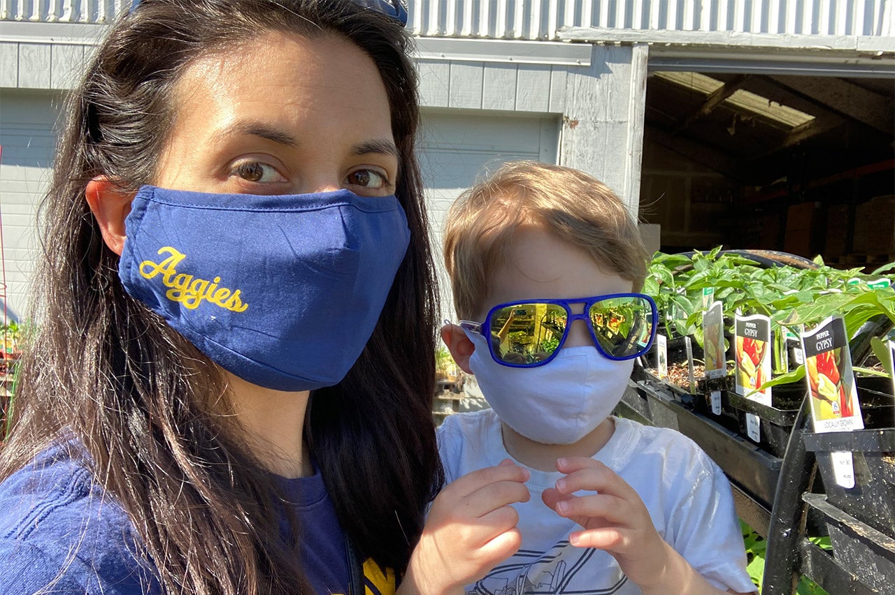 Woman with son, both wearing face coverings, at plant nursery.