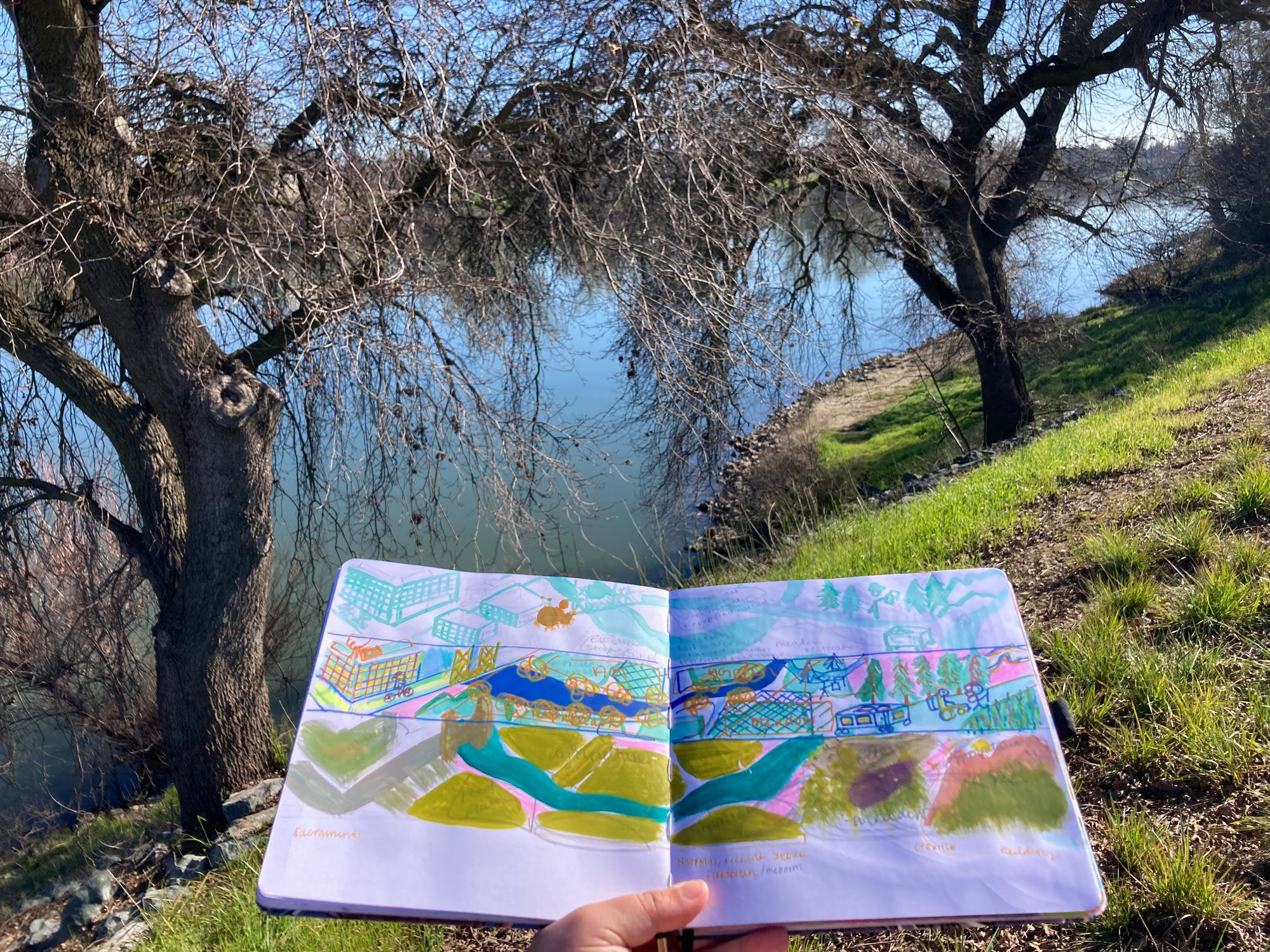 Unseen person holds mural drawing along riverbank