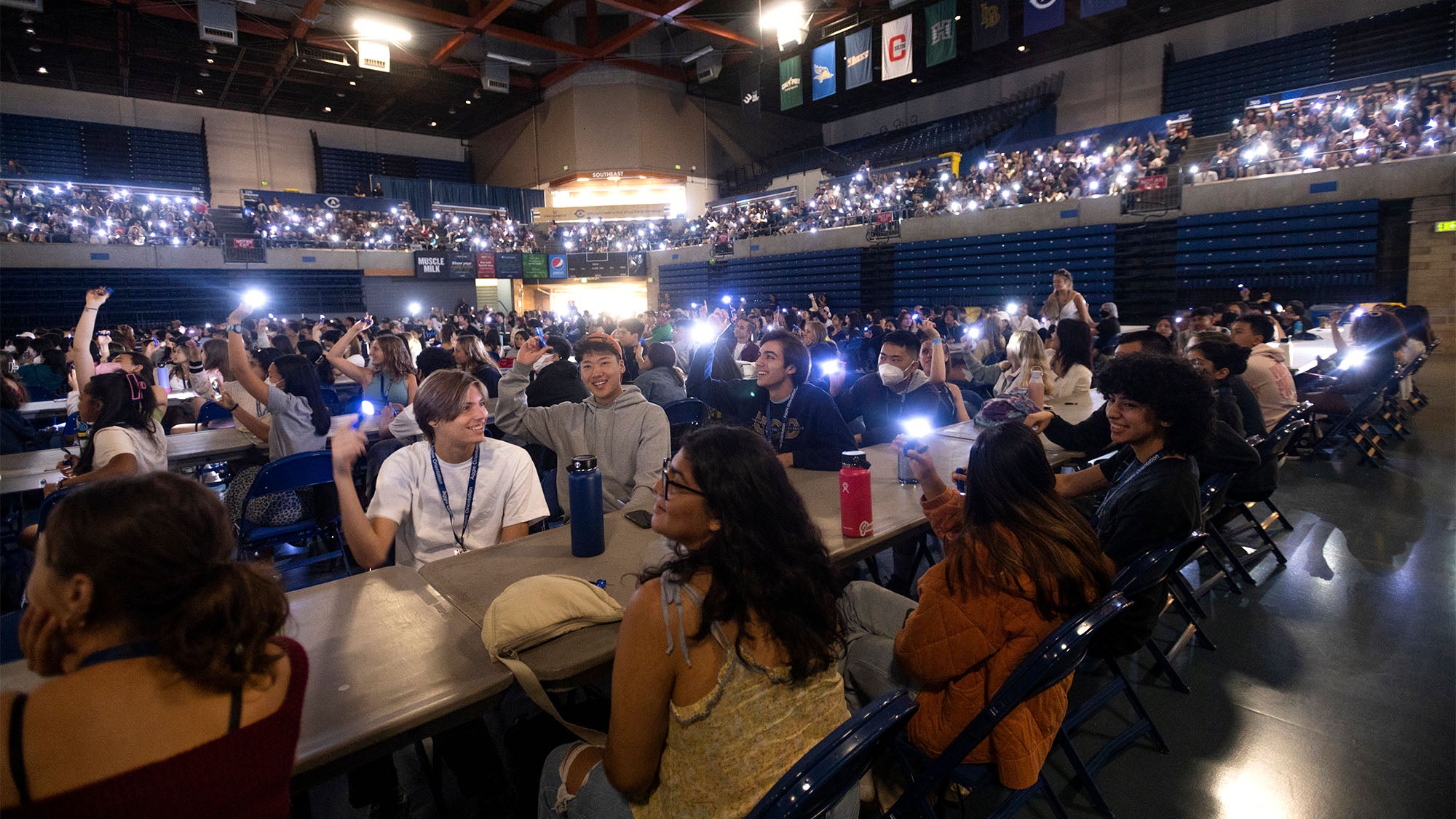 Students hold flashlights in The University Credit Union Center