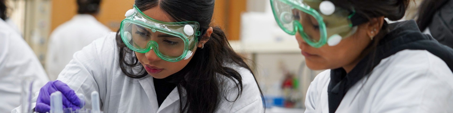 two chemistry tudent wear goggles at a lab bench while dealing with pharmaceuticals at UC Davis