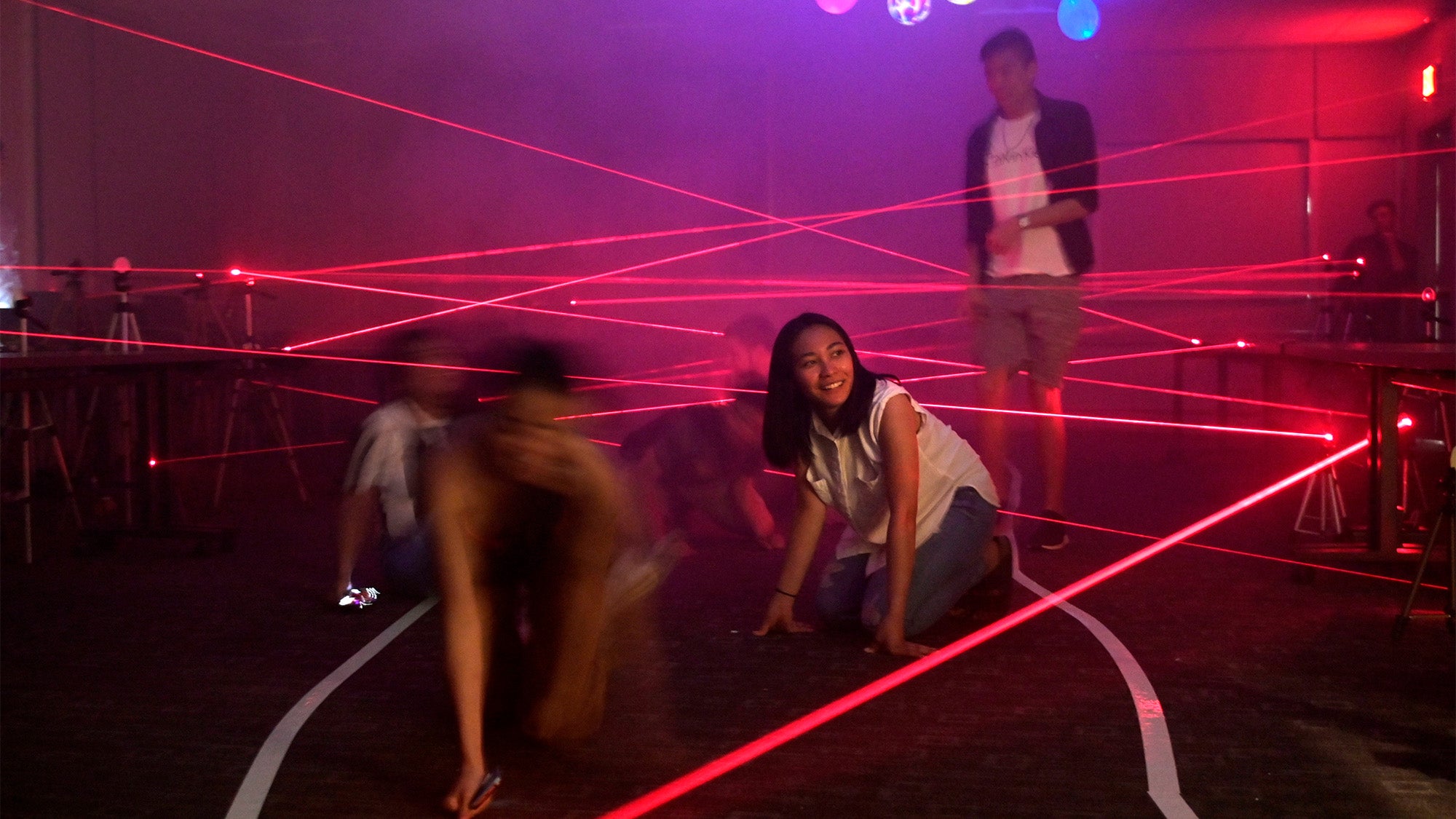 Students navigate through a dark room filled with laser beams.