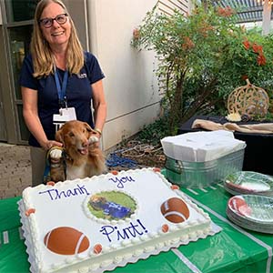 Pint the dog and his owner pose for photo next to cake