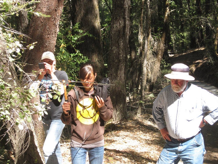 Vickie Chaimanont walks through the woods with research equipment at UC Davis.
