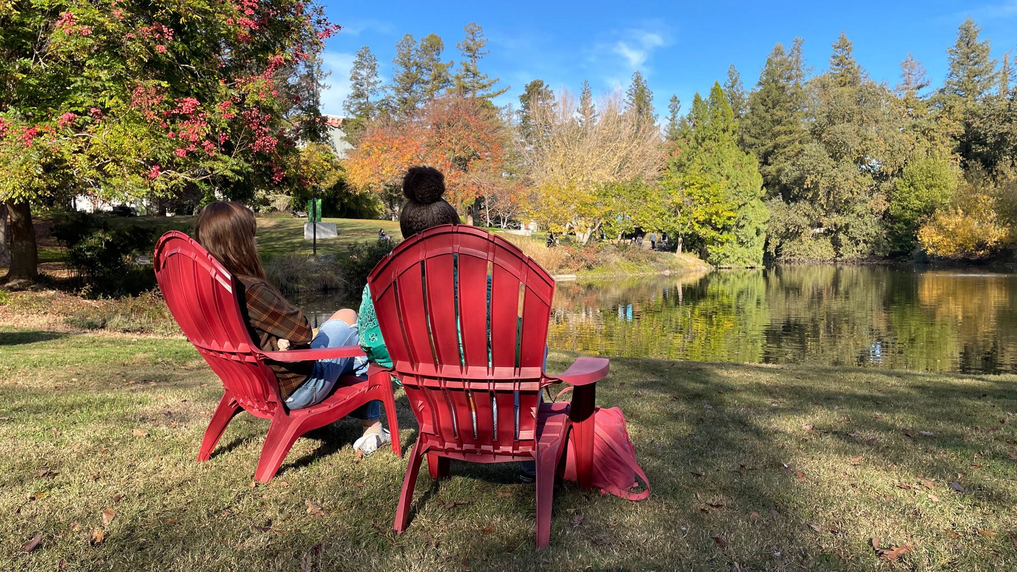 People sit in Adirondack chaiurs along Lake Spafford