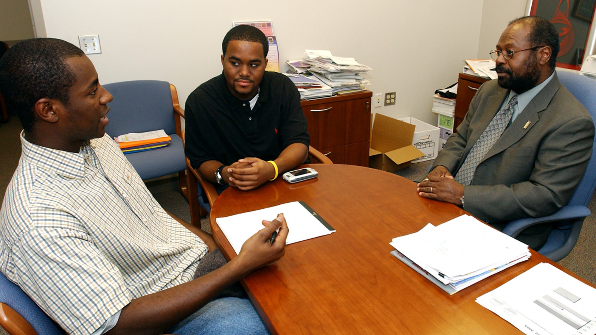 Reed and two students, in discussion, at a table