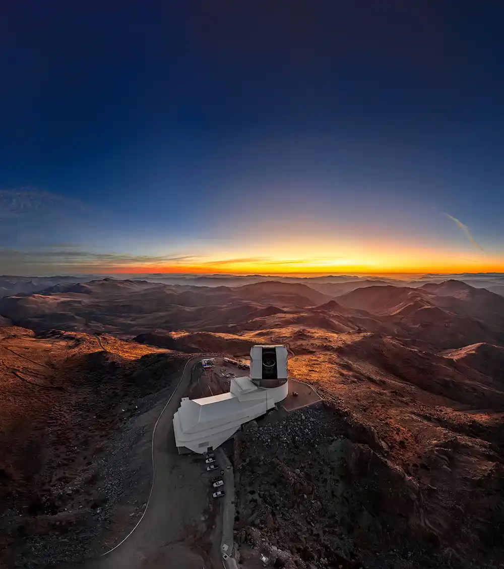 White mountain observatory overlooking rugged peaks at sunset with glowing horizon