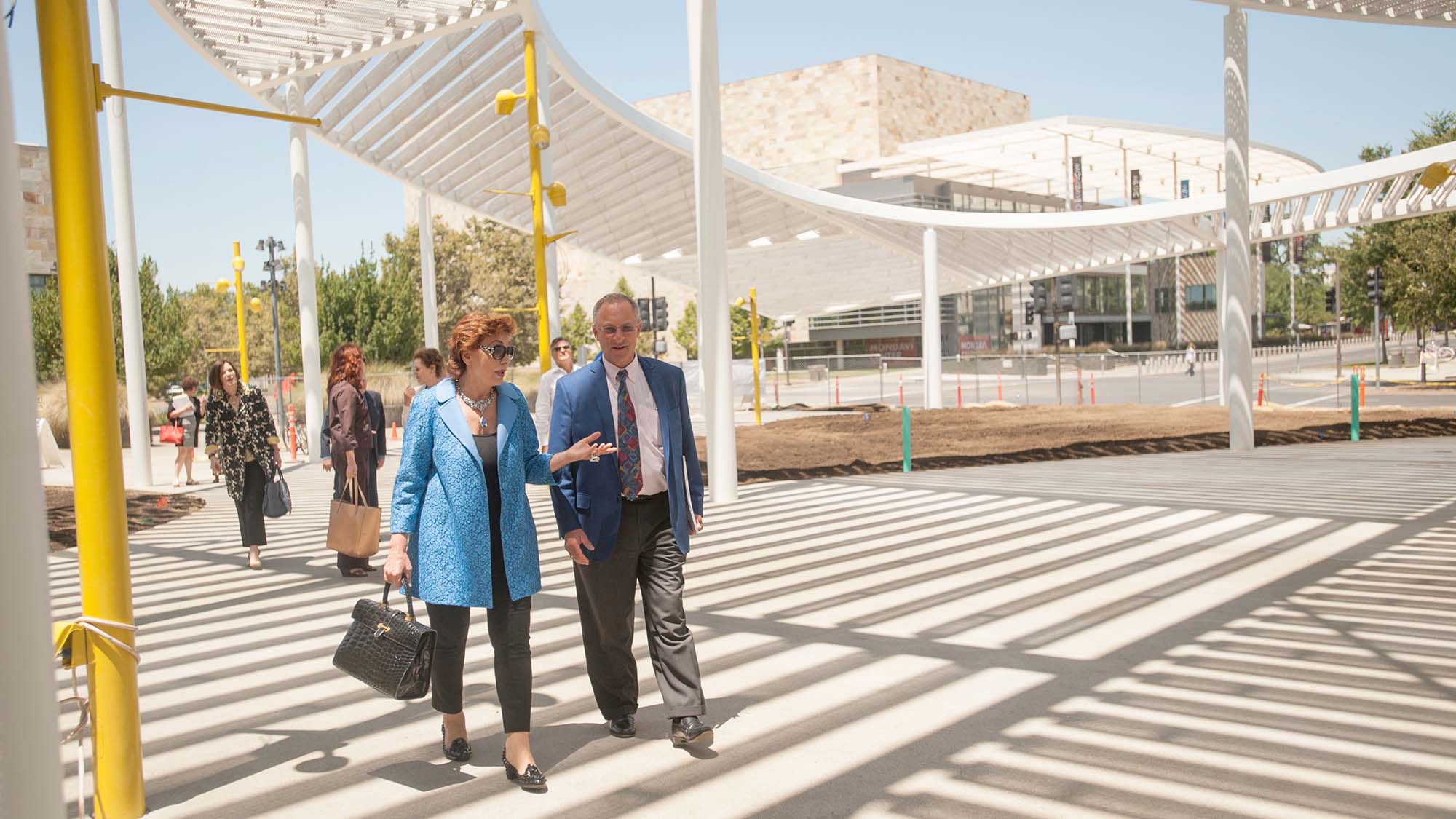 Maria Manetti Shrem walks with Ralph Hexter under the overhang outside the Jan Shrem and Maria Manetti Shrem Museum of Art.