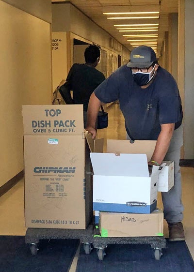 A worker carts items through a hallway.