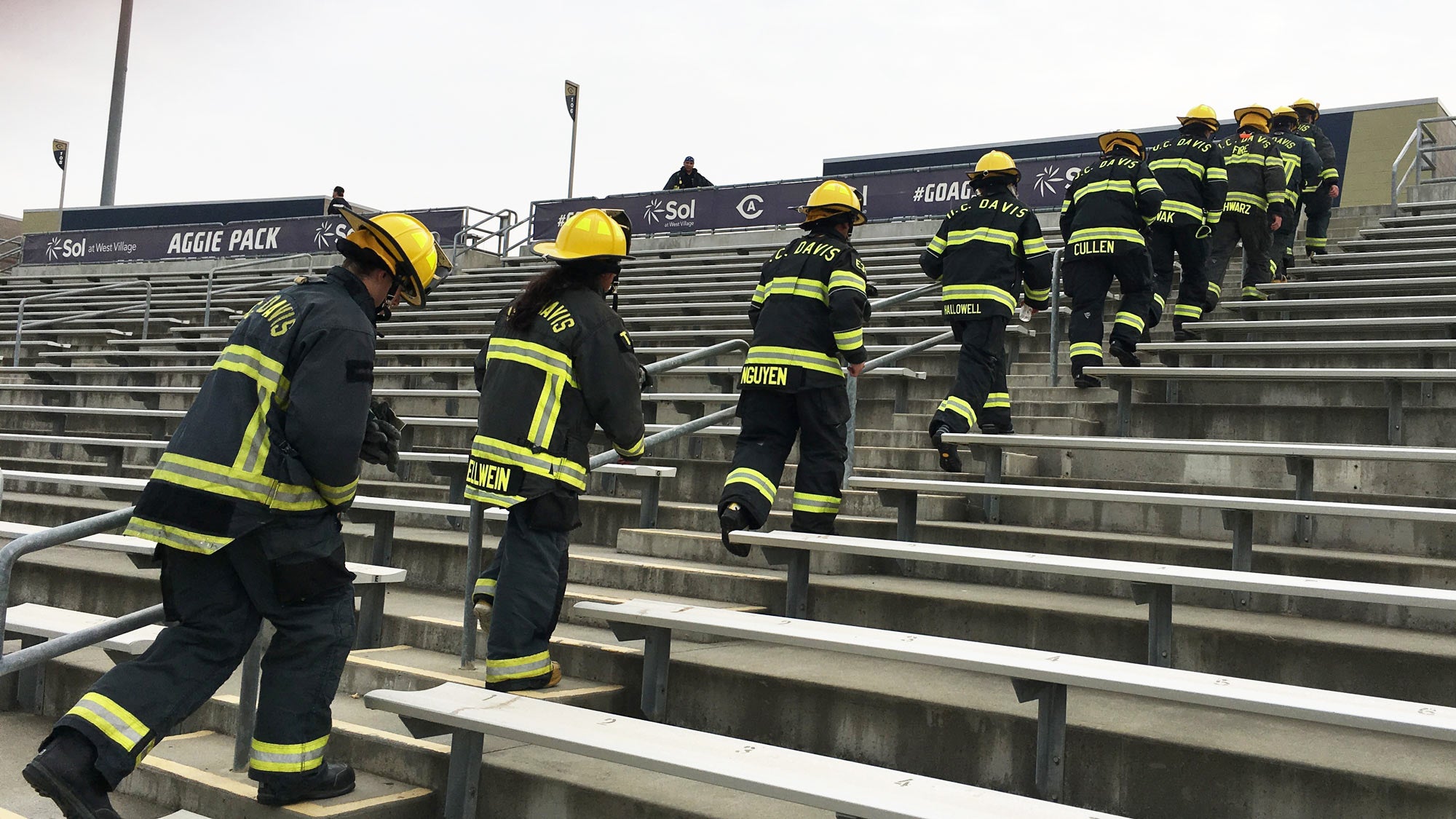 Student firefighters in turnouts walk up stairs