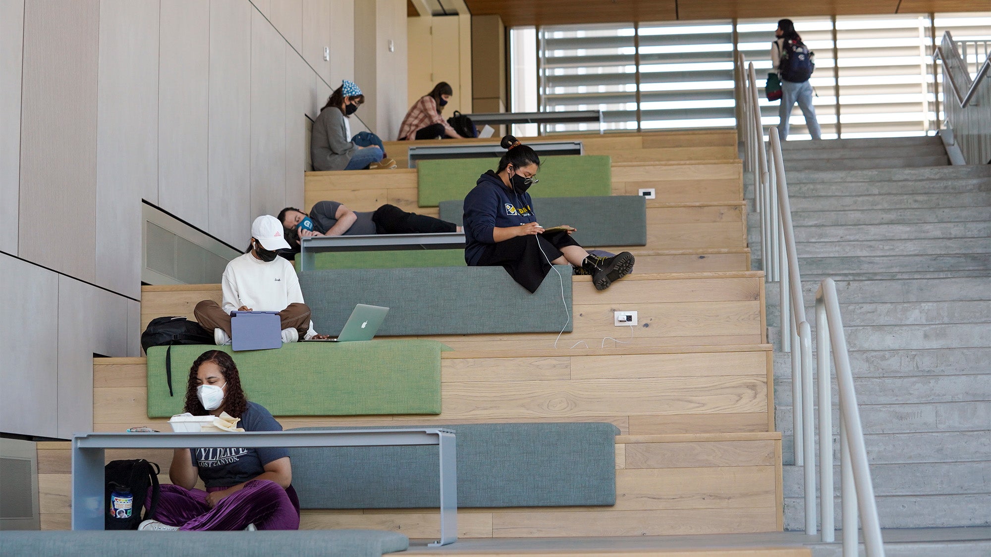 Students sit on stairs at the Teaching and Learning Complex