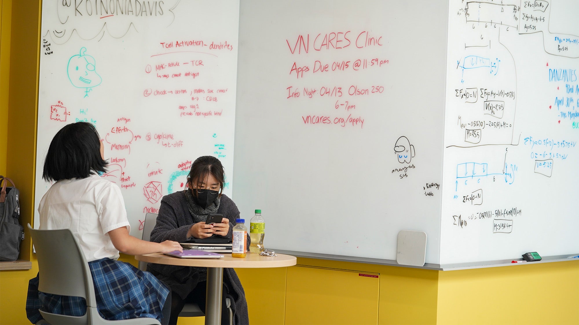 Students study next to large whiteboards