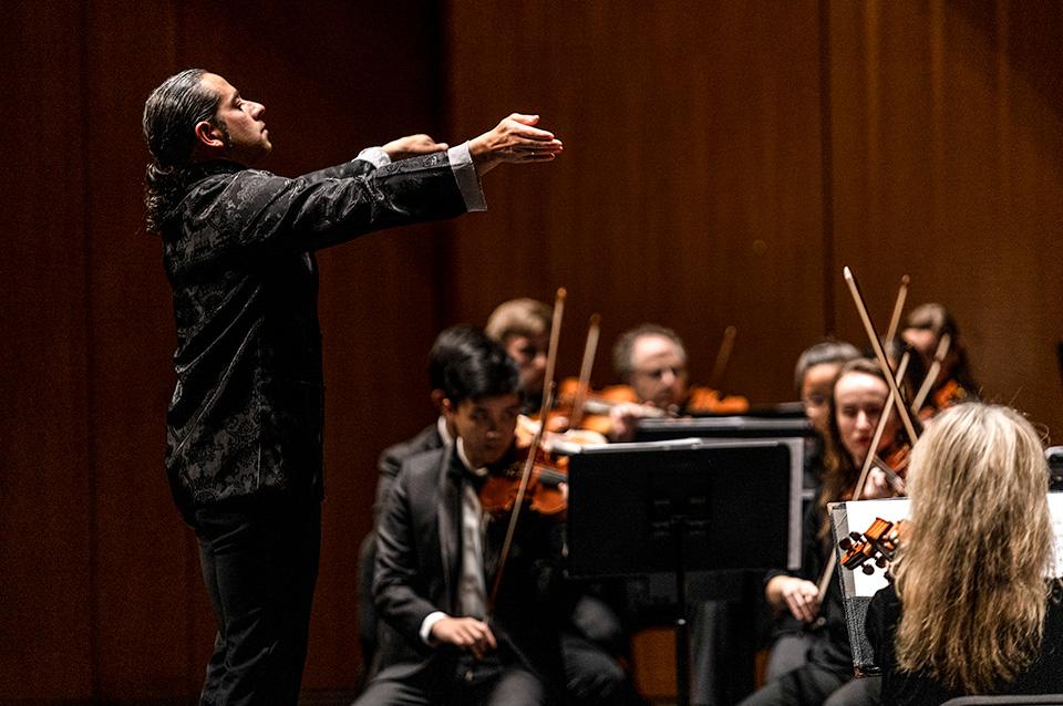 Conductor directs orchestra on stage