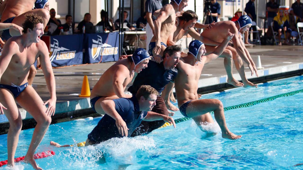 Water polo players celebrate by jumping into the pool