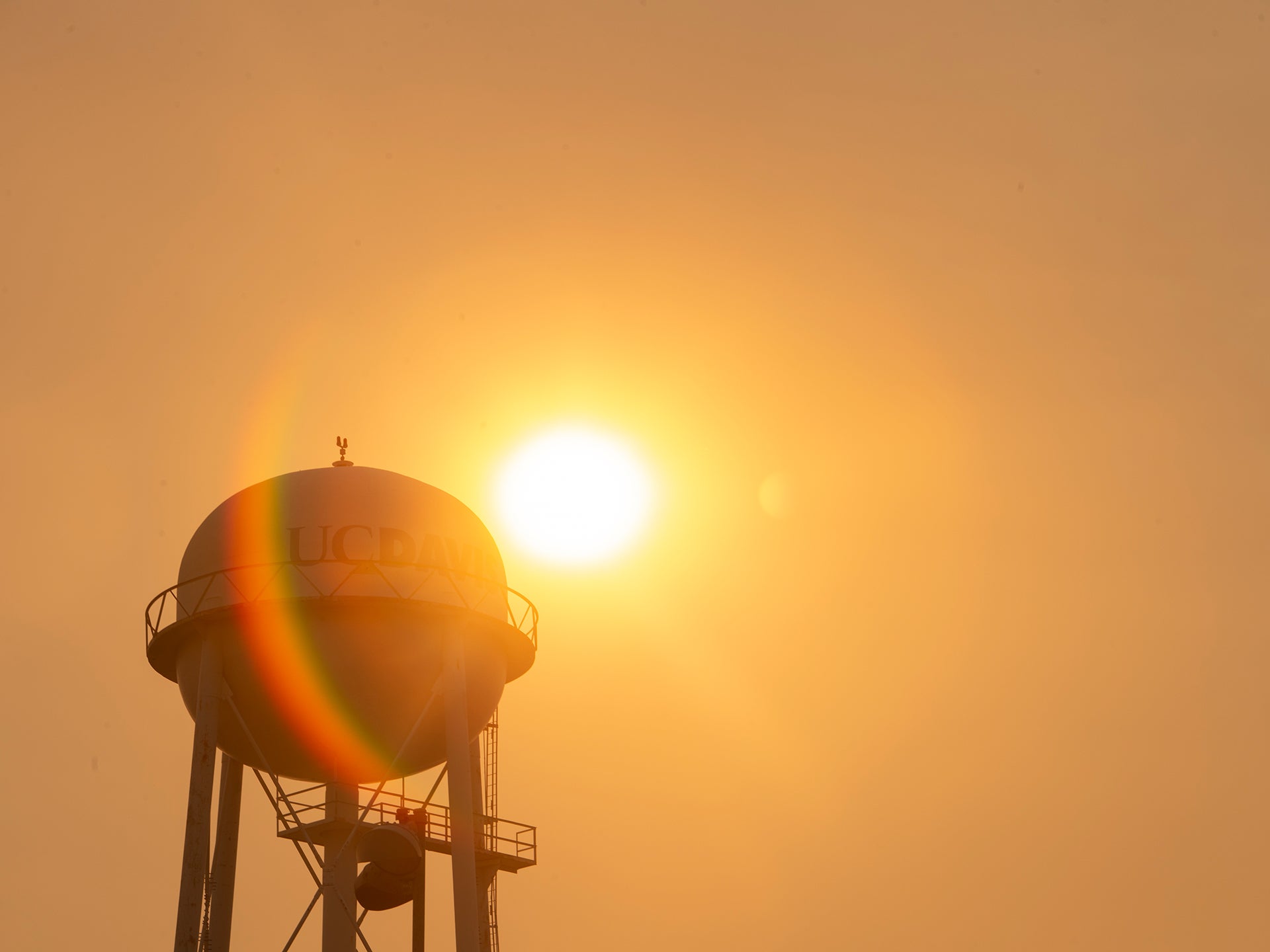 The sun rises in a haze of smoke over the UC Davis water tower.