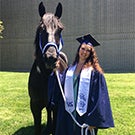 A graduate posing with a horse