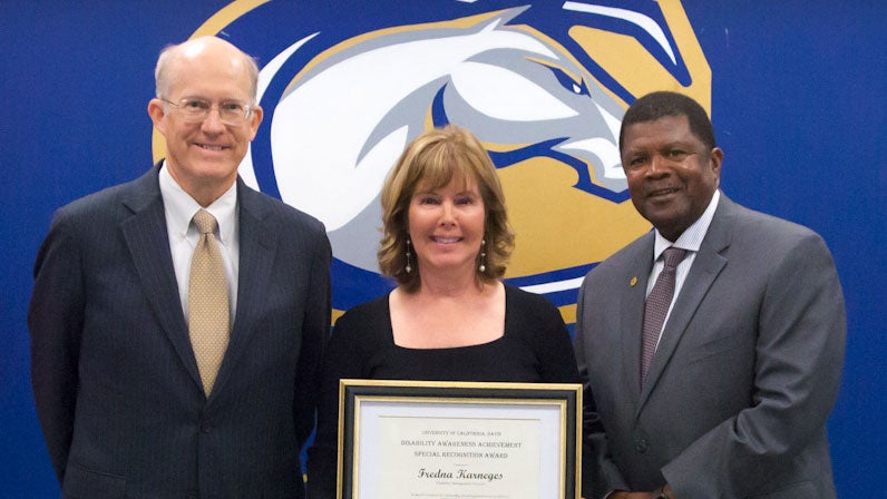 Fredna Karneges holds award plaque; she is flanked by Ken Burtis and Walter Robinson.