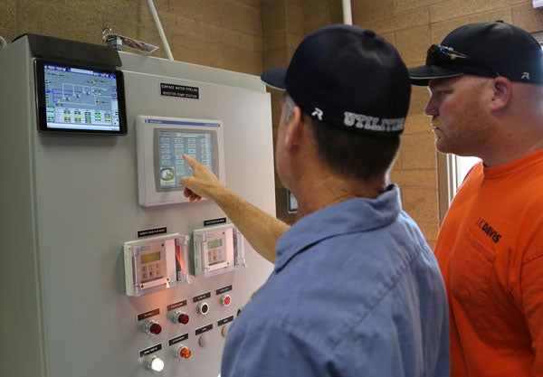 Two men tend to computerized water control system.