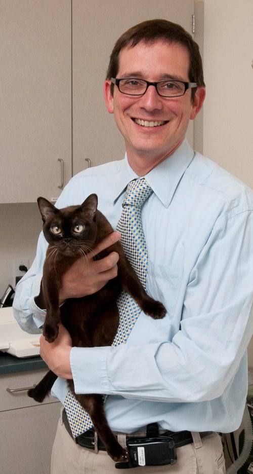 Michael Kent holding a cat in exam room