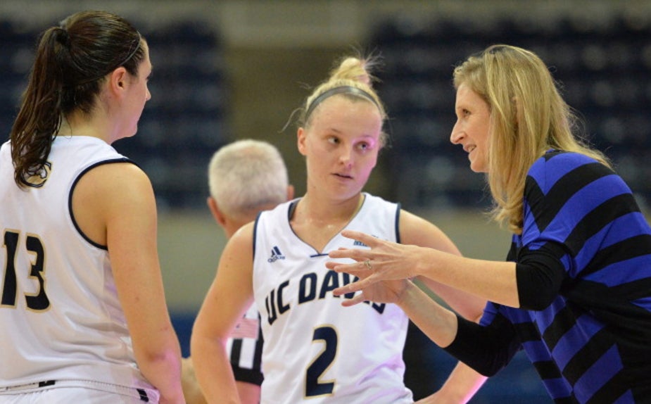 Coach Jen Gross talks to two players during a game.