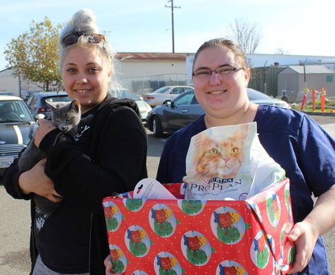 Volunteer gives Holiday pet Basket to a woman and her cat.