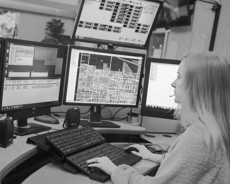 Female dispatcher at console of multiple computers and keyboards