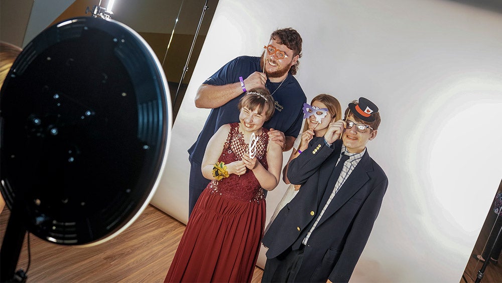 Student poses in photo booth with date and other prom attendees.