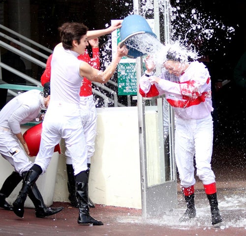 Jockeys throw water on first-time winner.
