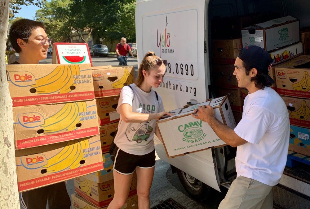 Student volunteers unload food from van.