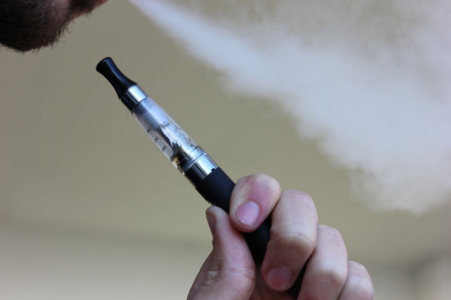 E-cigarette in hand, smoke coming from user's mouth