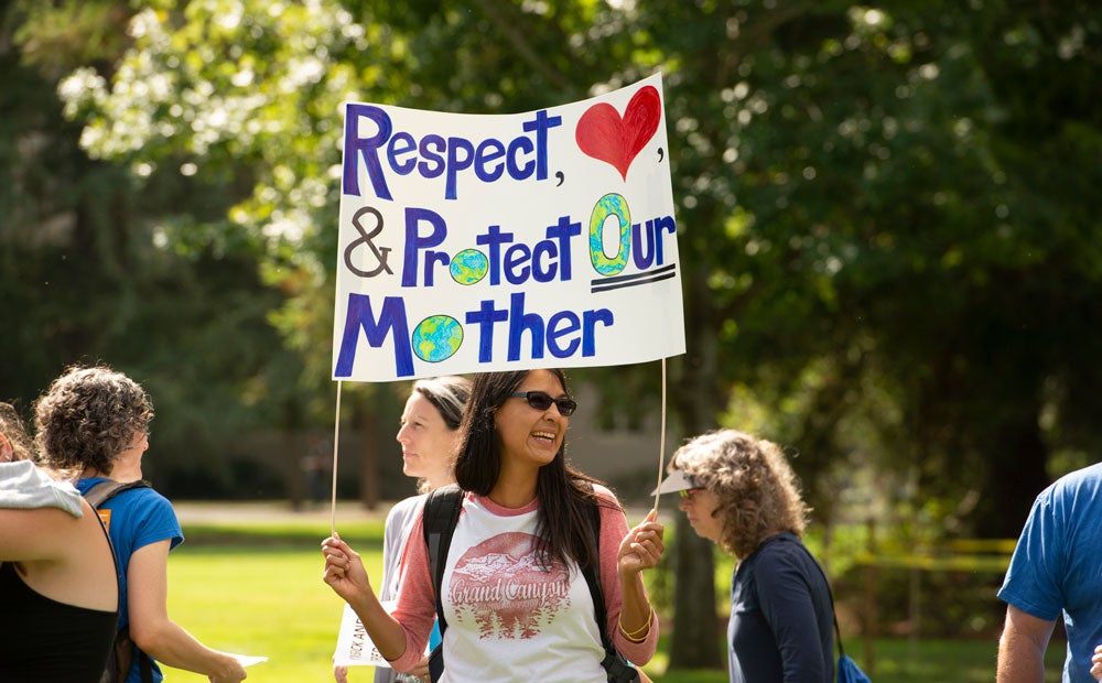 Climate striker, female, holds sign, "Respect, Love & Protect Our Mother (Earth)."