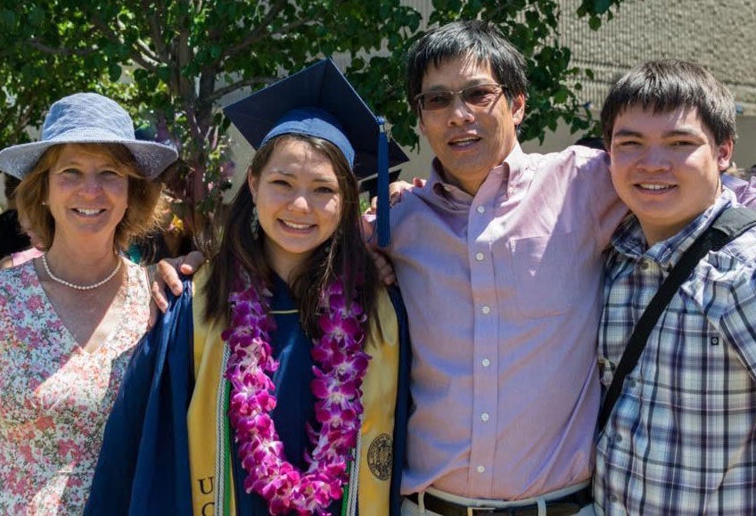 Kendra Chan in UC Davis graduation gown, posing with her family.