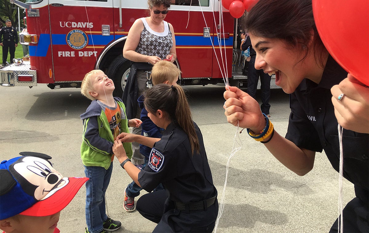 Students hand out balloons to young kids at the fire department.