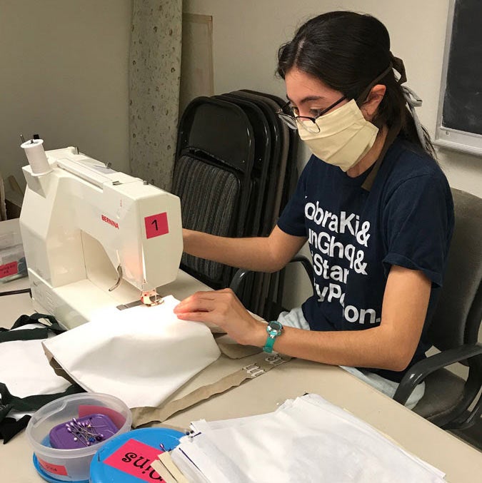 Woman sews face mask at sewing machine.