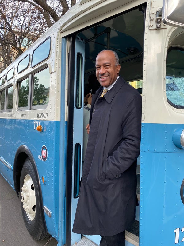 Chancellor Gary S. May on step leading into historic bus.